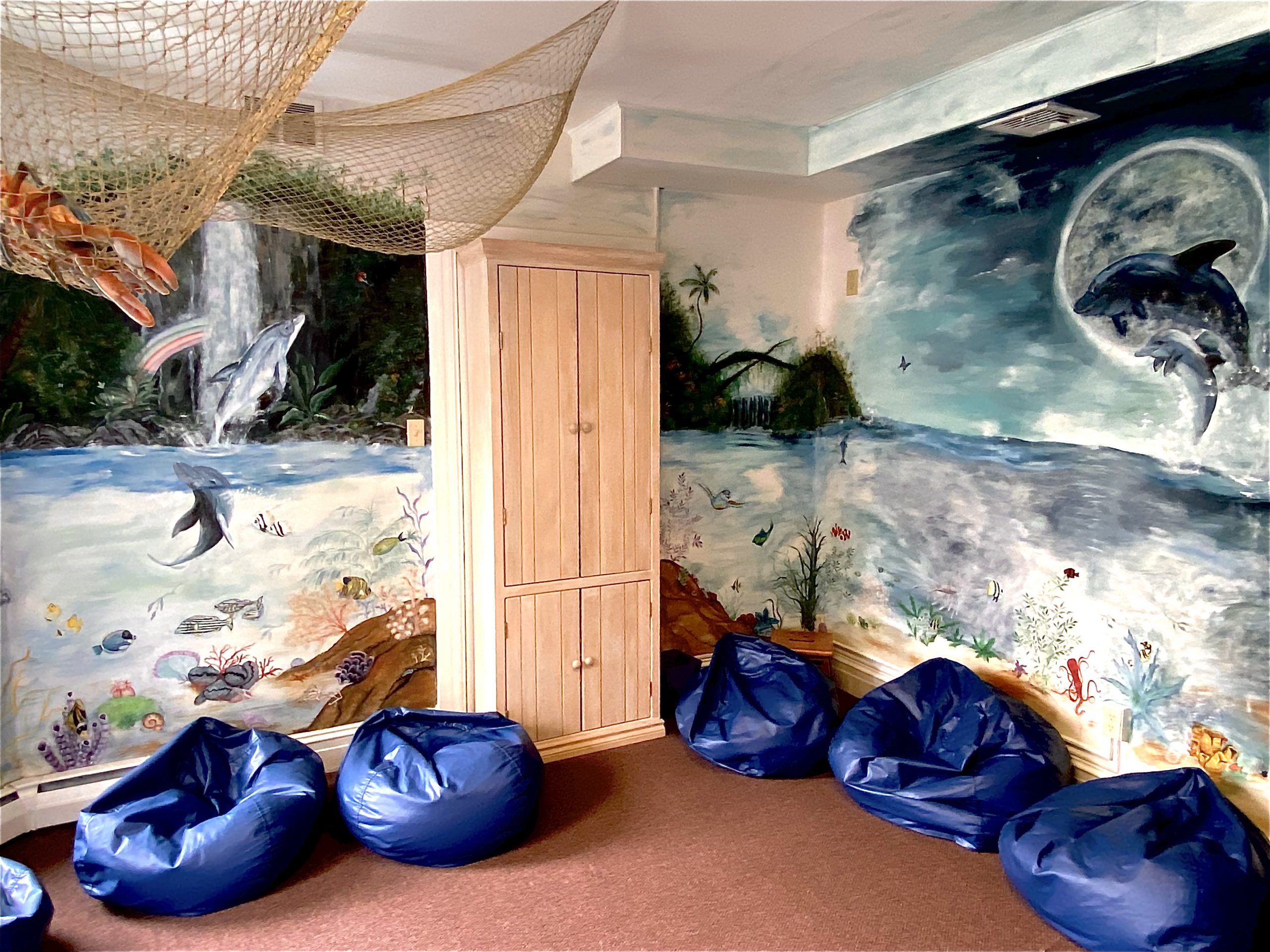 Middle school age children occupy the Dolphin Room, designed to support their need for peace and serenity amidst the chaos. The mural depicts the role a dolphin plays in rescuing a drowning person! The beautiful symbolism and deeper meaning serve this age group well.